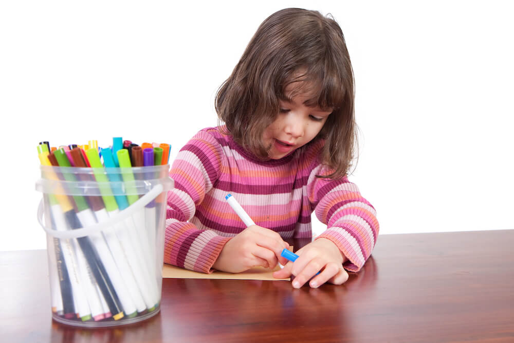 Child drawing on paper with a magic marker