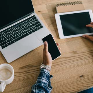 Man looking at computer, phone, and tablet while having coffee