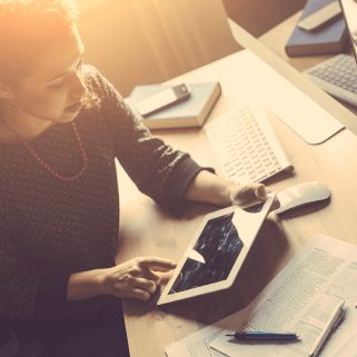 Young, female entrepreneur looking at tablet computer with sunlight coming in from behind