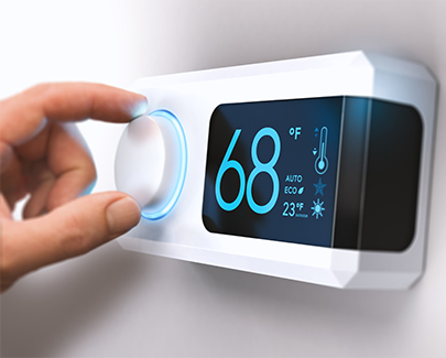 Hand adjusting a thermostat with a cyan digital display