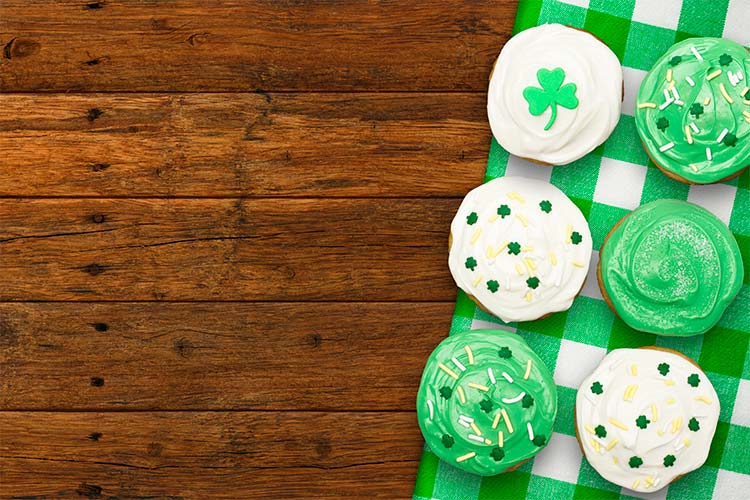 Green and white cupcakes on a green, gingham tablecloth on a wooden table