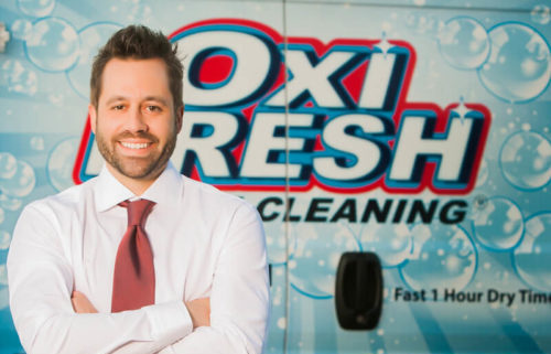 Jonathan Barnett, leader of the carpet cleaning franchise company, standing in front of the back of an Oxi Fresh Carpet Cleaning van