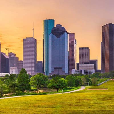 Shot of the Houston Skyline at sunrise, faint yellow and pink light serving as a backdrop to the blue and gray skyscrapers