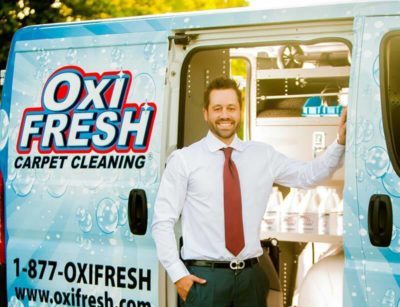 Jonathan Barnett stands at the side of an open Oxi Fresh van. Products can be seen in the background.