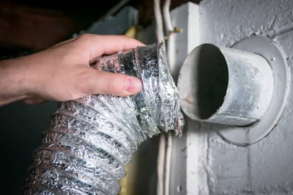 A dryer vent cleaning technician inspects a dryer vent.
