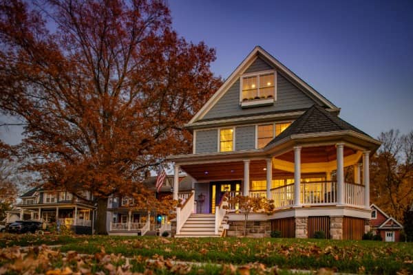 Outdoor shot of a home in the fall months with leaves on the ground and a colorful tree in the yard.